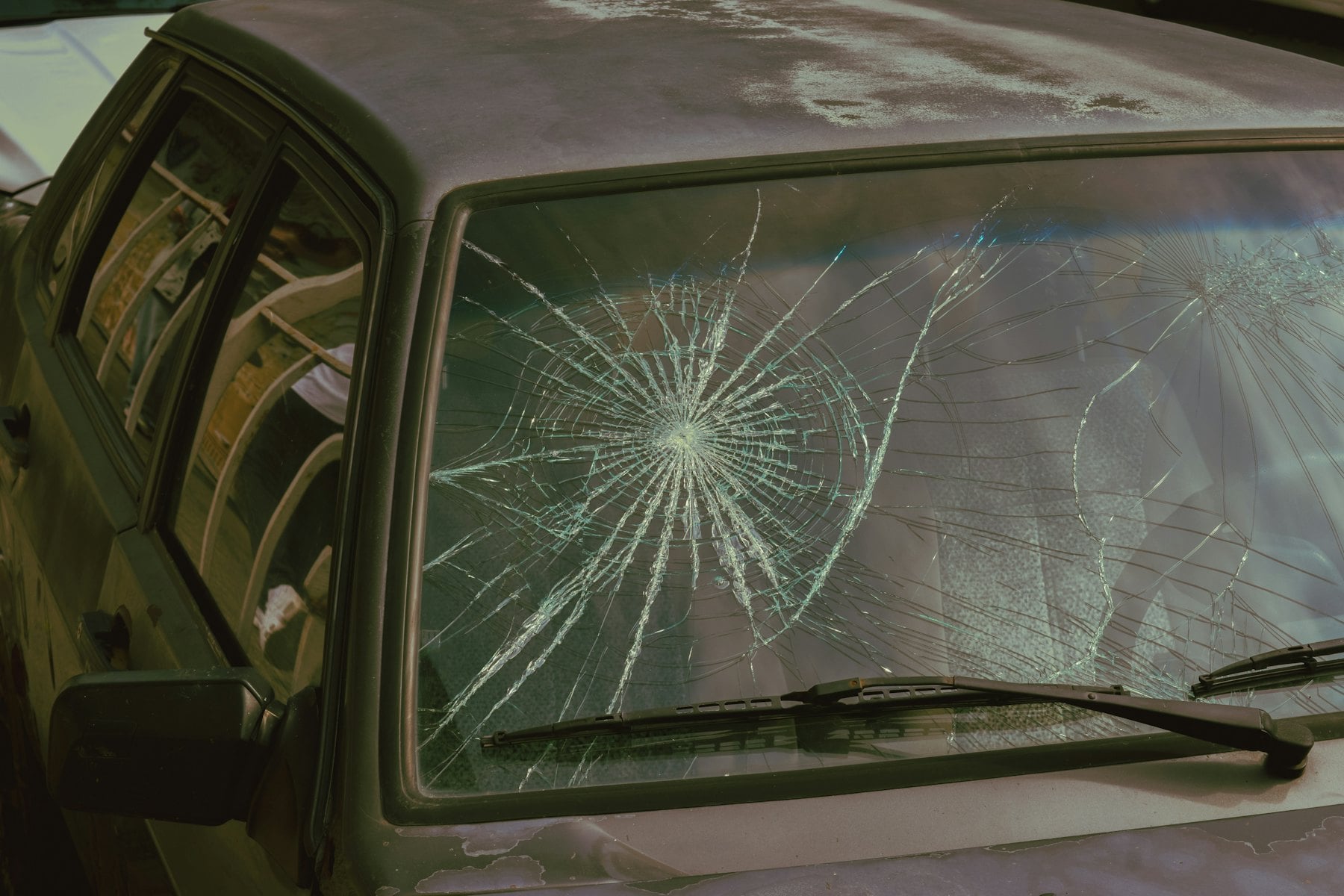 Cracked car windshield with spider-web damage from a rock impact